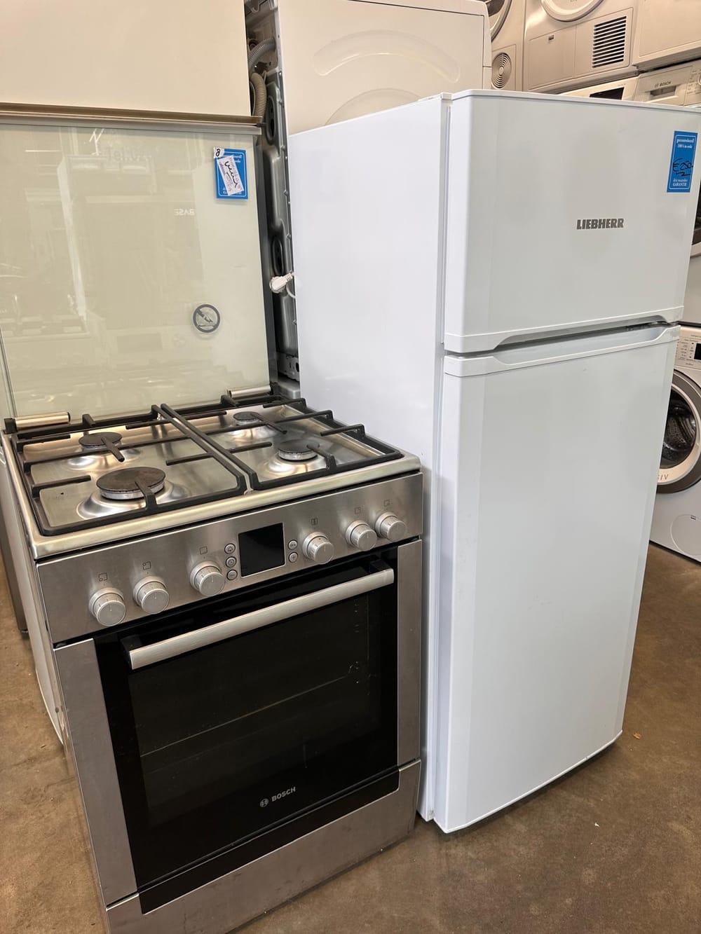 Een gasfornuis met oven naast een koelkast in de winkel